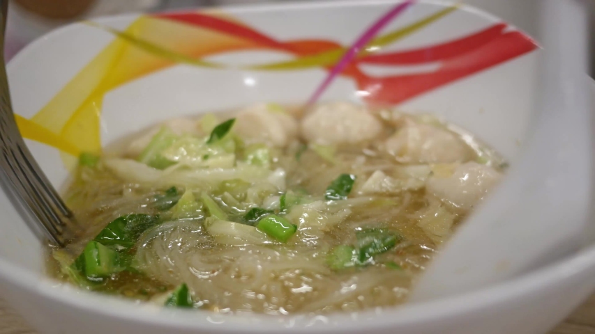Close up of Hands mixing a noodles meal with a fork and spoon in restaurant.
