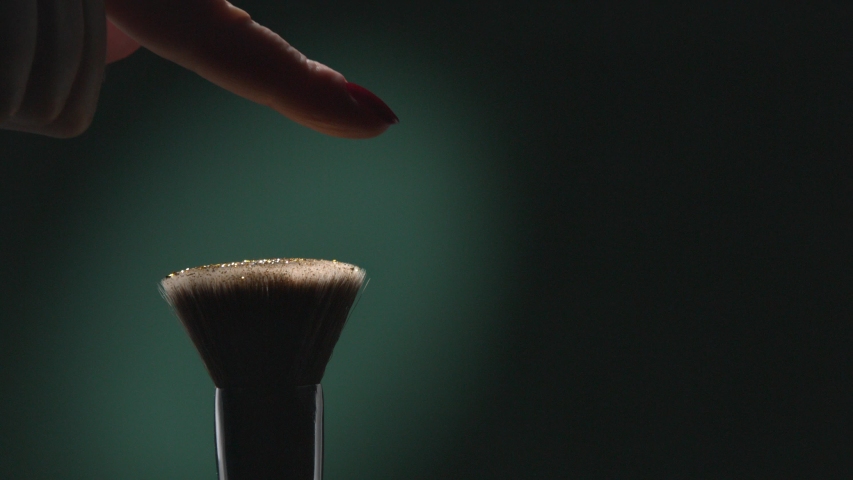 Glitter on a Make-up Brush Flying Away with Woman Finger Flicking Shot in Slow Motion on Green Aqua Menthe Color Background Royalty-Free Stock Footage #1043766691