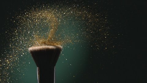 Glitter on a Make-up Brush Flying Away with Woman Finger Flicking Shot in Slow Motion on Green Aqua Menthe Color Background