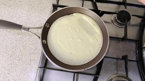 The process of making traditional Russian thin pancakes in a frying pan. Close up 4k 60 fps video of mother flipping baking homemade breakfast dessert for children. top view