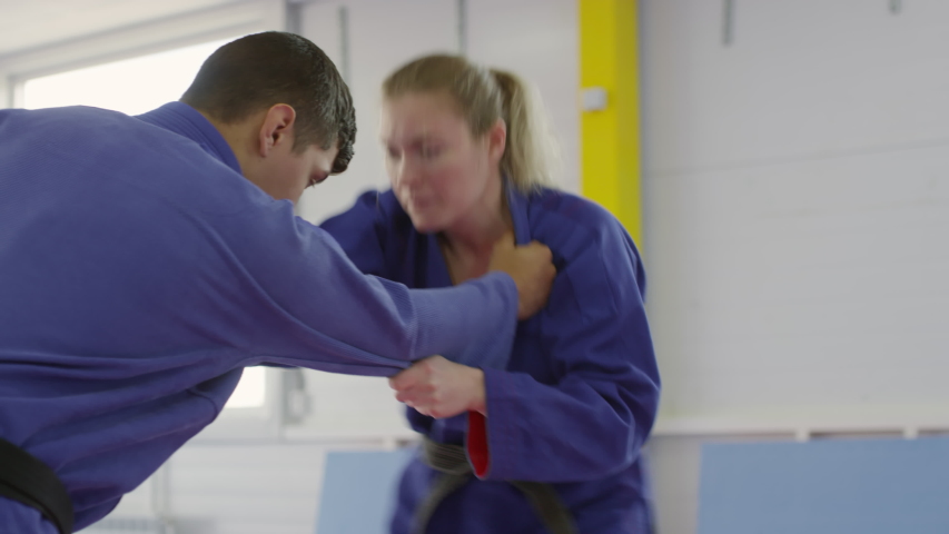 Tilt down shot of female martial arts athlete performing takedown during jiu-jitsu practice with male partner Royalty-Free Stock Footage #1043775466