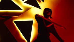 Footage of professional swag, freestyle or hip hop dancer . Stylish young masked girl dancing against colorful background with triangle shape of led lights . Shot on ARRI ALEXA Cinema Camera .
