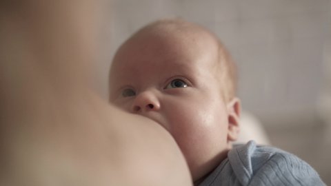 Close portrait of feeding newborn baby looking on mother. 4K