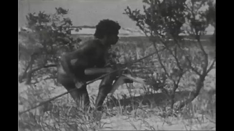 CIRCA 1935 - An aboriginal man watches Captain Cook and his men land on an Australian beach in 1770.