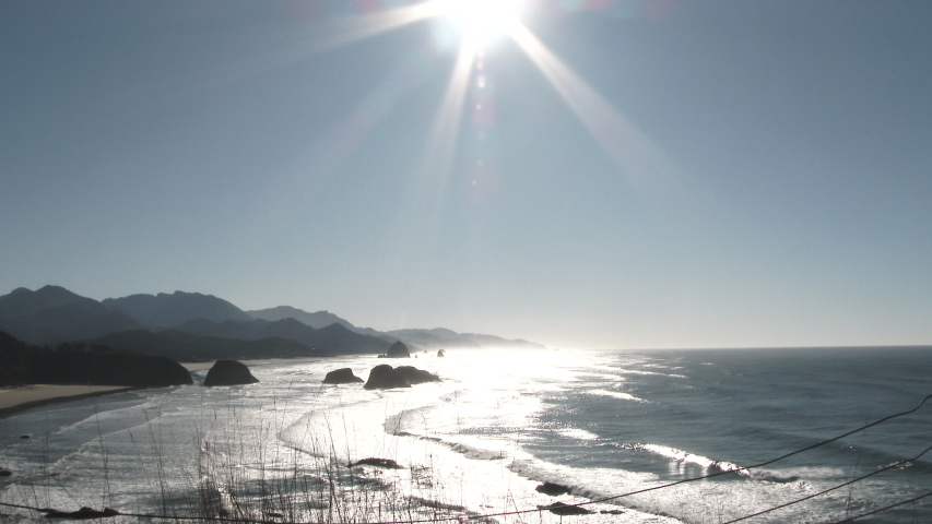 Person enters frame and looks out over the Oregon coastline on beautiful sunny and clear blue sky day.
