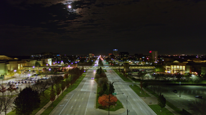 Detroit Michigan Aerial Fly over of Beaver road looking toward downtown skyline with plane take off and moon sky - October 2017