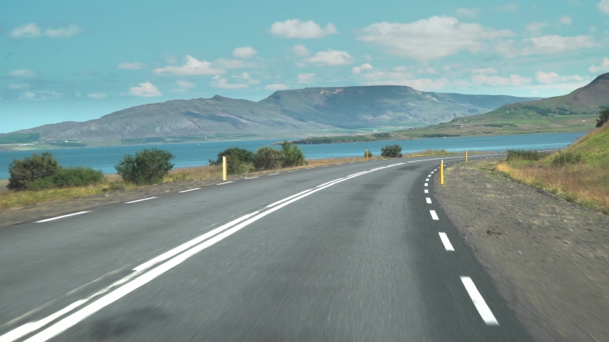 Car driving on the road to Iceland. View of the road, mountains and the bay from the inside of the car. Road number 1 is Iceland