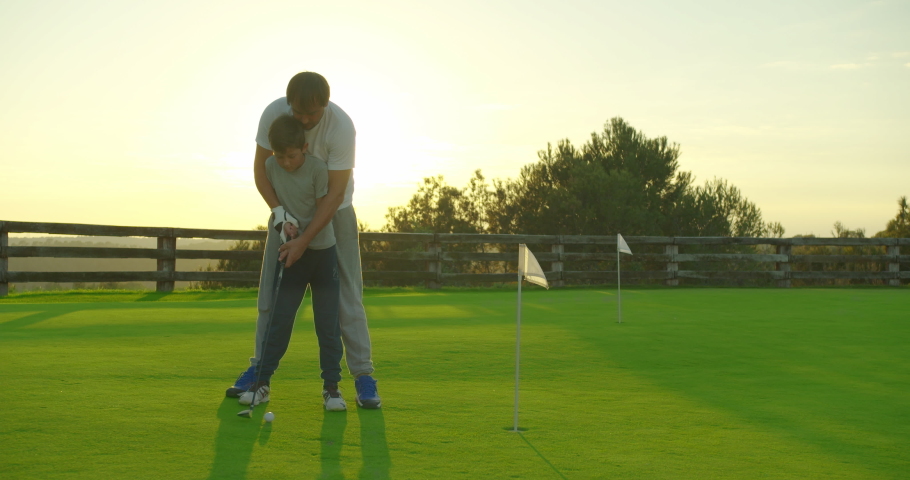 Man with his son playing golfers on perfect golf course at summer day. Royalty-Free Stock Footage #1043813869