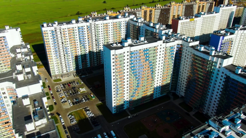 Construction of new high rise buildings with colorful facades on a summer sunny day. Motion. Aerial view of new district in the sleeping area of the city.