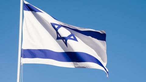 State Flag of Israel. The Big State Flag is illuminated by the sun and flutters epically in the wind against the blue sky. Slow Motion 120 fps