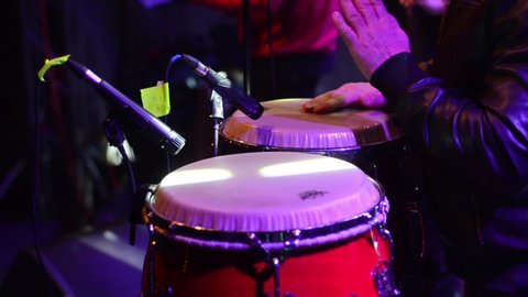Man hands playing Conga drums at music concert under the stage lights. Musician playing the congas at festival, close-up. Timpanist. Rhythm of Africa. Young drummer.  
