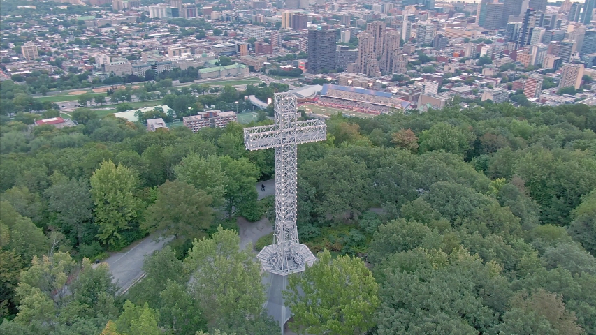 AERIAL: Flying over the cross structure on Mont Royal. In the distance is Montreal city skyline. Quebec, Canada