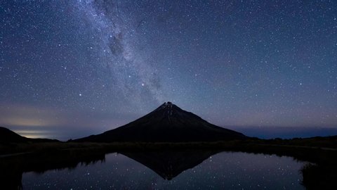 a timelapse of the milkyway going behind the Taranaki mountain and it's reflation in a lake