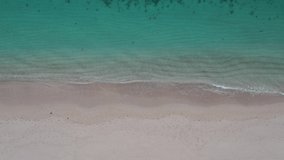 Top down drone video of sandy beach and blue sea 