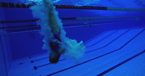 4K Under water view of professional female swimmer . Underwater footage of woman jumping into water . Swimmer jumping in big swimming Woman swimmer dive in water pool .  Slow Motion .