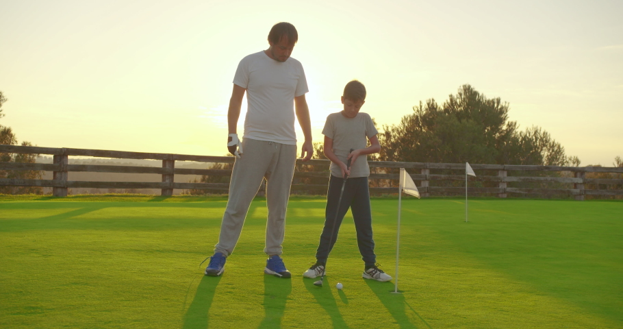 Man with his son playing golfers on perfect golf course at summer day. Royalty-Free Stock Footage #1043867089