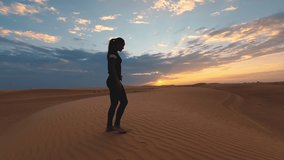 Silhouette of a young woman doing yoga at sunset in the huge desert. Epic sunset and sport concept video.