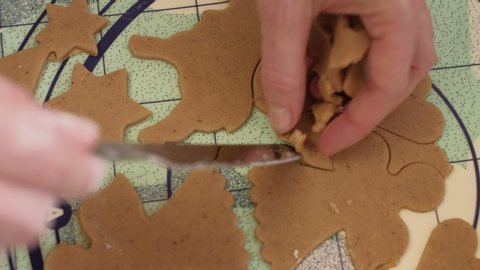 Women hands removing excess dough from around freshly cutted ginger Christmas cookies. 4K resolution close up shot on gimbal.