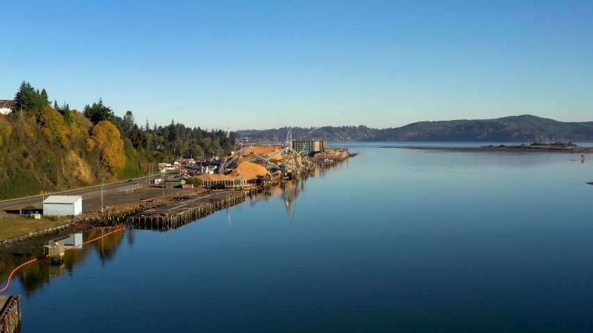 Sunny, smooth aerial dolly over Coos Bay and mill in Pacific Northwest