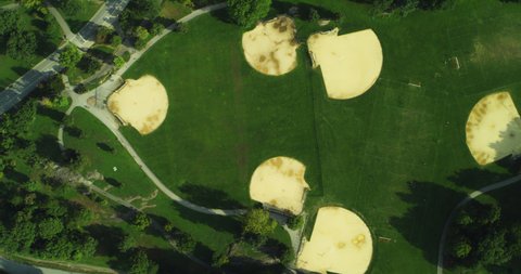 Aerial top down view of city park space with baseball diamonds near water in New York during the day under blue skies. Wide shot on 4K RED camera.