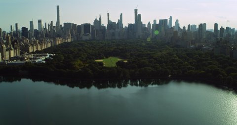 Aerial view of Central Park and Manhattan skyine in New York during the day under blue skies. Wide shot on 4K RED camera.