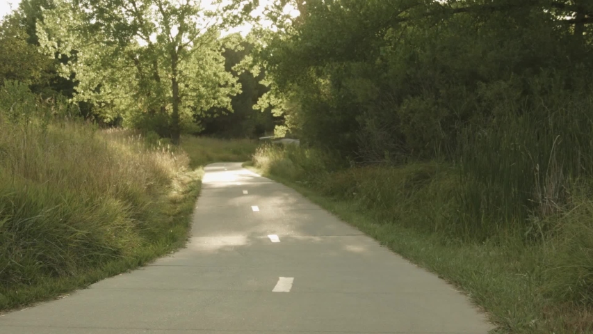 Winding bike trail in a forest at sunset with cyclists pedaling up and down the trail on either lane