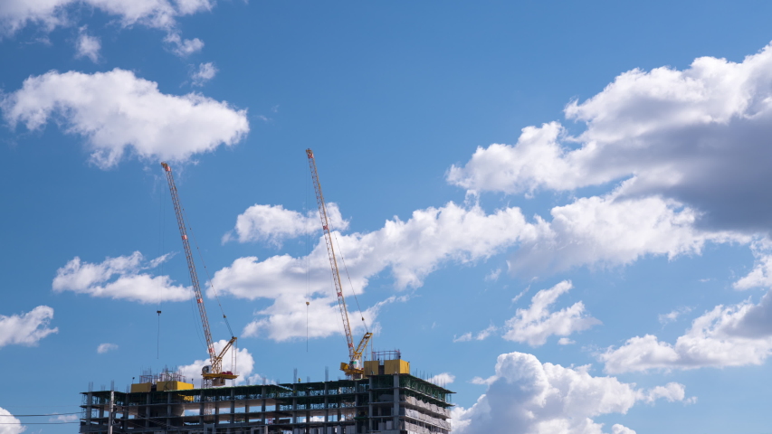 Clouds flow over building construction in blue sky 4K timelapse 