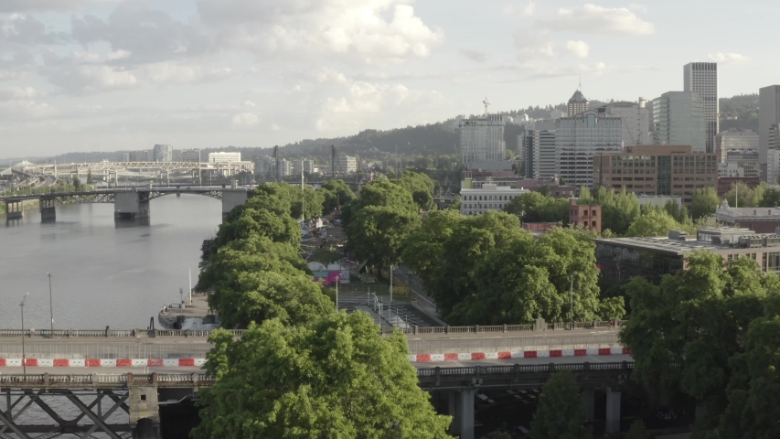 A captivating aerial view of the waterfront park with the Steel Bridge in the background shot in 4K. Portland. Oregon. USA. The bridge links the Rose Quarter and Lloyd District in the east to Old Town