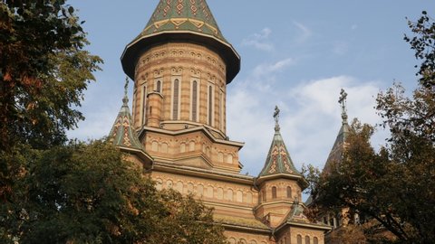 Sun light on facade and tower of Orthodox Metropolitan Cathedral in Timisoara slow tilt 4K video