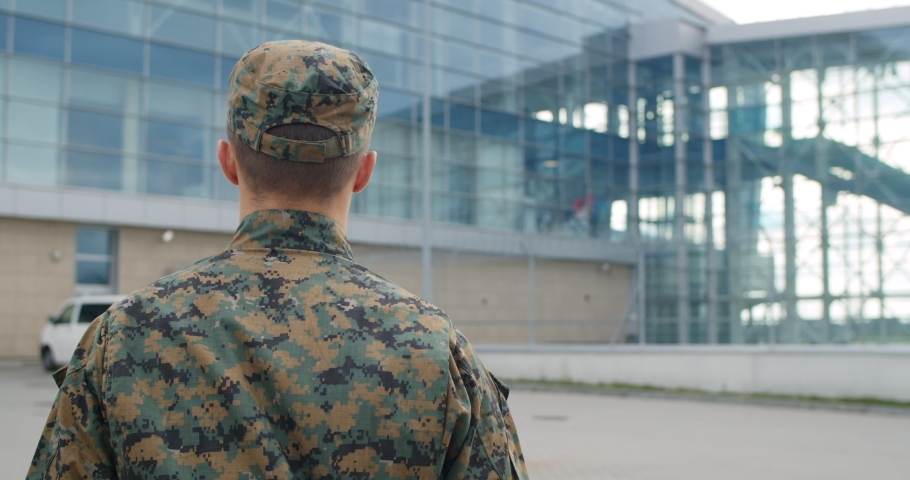 Back view of male soldier leaving on military service. Man in military uniform putting bag on shoulder and walking to airport terminal. Concept of military service, army, duty Royalty-Free Stock Footage #1043915632