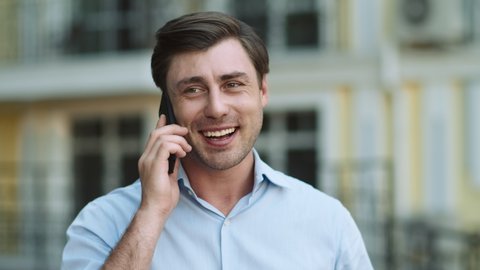 Portrait handsome man having phone talk outdoor. Business man talking on smartphone at street. Happy man call phone outdoor. Office employee talking mobile phone outside