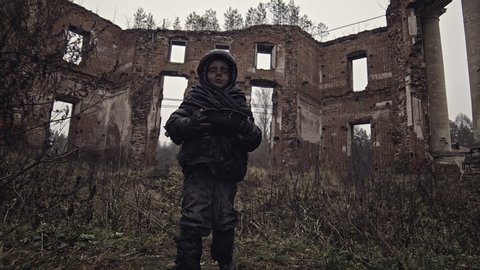 Homeless boy carries water in a bowl on the ruins. War. Apocalypse. Catastrophe.