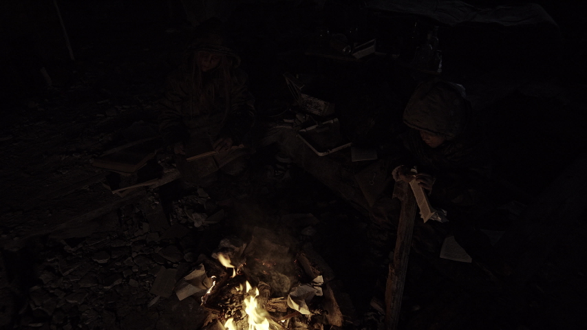 Homeless children bask in the ruins of a campfire. Apocalypse. War.
