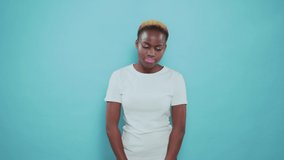 Front view of attractive african girl with short haircut wearing white t-shirt. Pretty young woman with sincere surprise emotions posing on blue background.