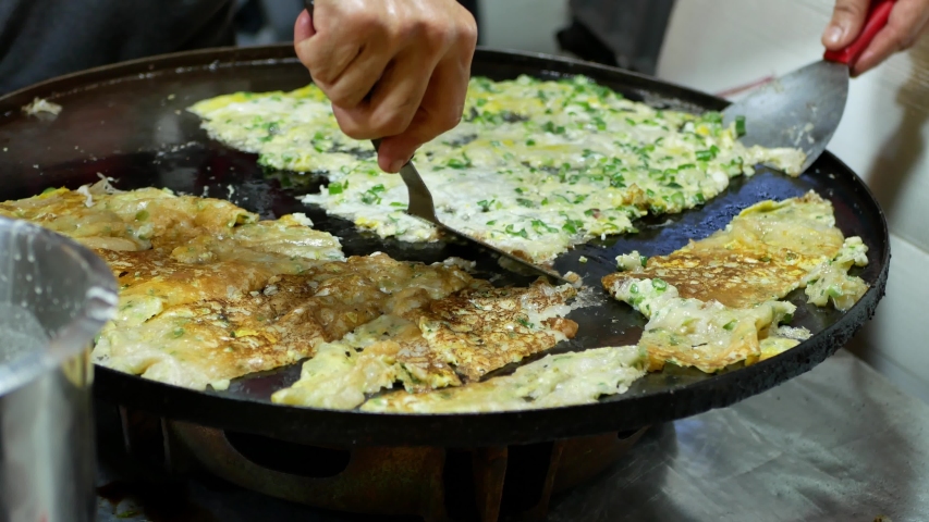 Street food vendor frying oyster omelette (Chinese Scallion Pancakes ) at the night market in Kuala Lumpur,Malaysia.