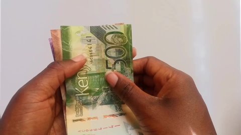 NAIROBI, KENYA - NOVEMBER 28, 2019: Two female Africa hands slowly counting Kenya bank notes. Taken in Nairobi, Kenya showing handling of finances.