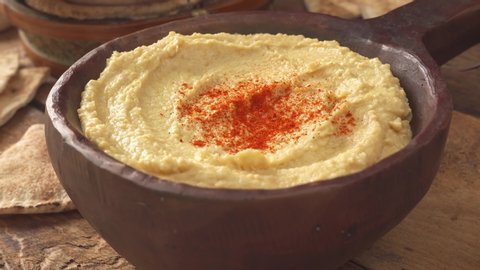 Hand dipping a pita chip into a delicious bowl of hummus.
