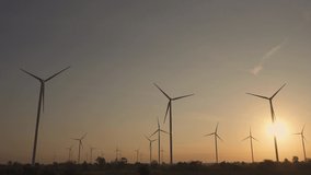 Wind turbines of save Energy save world in video 4k format. aerial shot on sunset. drone footage wind turbines at sunrise with beautiful clouds. Global warming concept and green energy.
