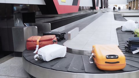 Luggage on a conveyor belt in the baggage claim area of international airport. Bags and backpacks moves at rubber carousel belt