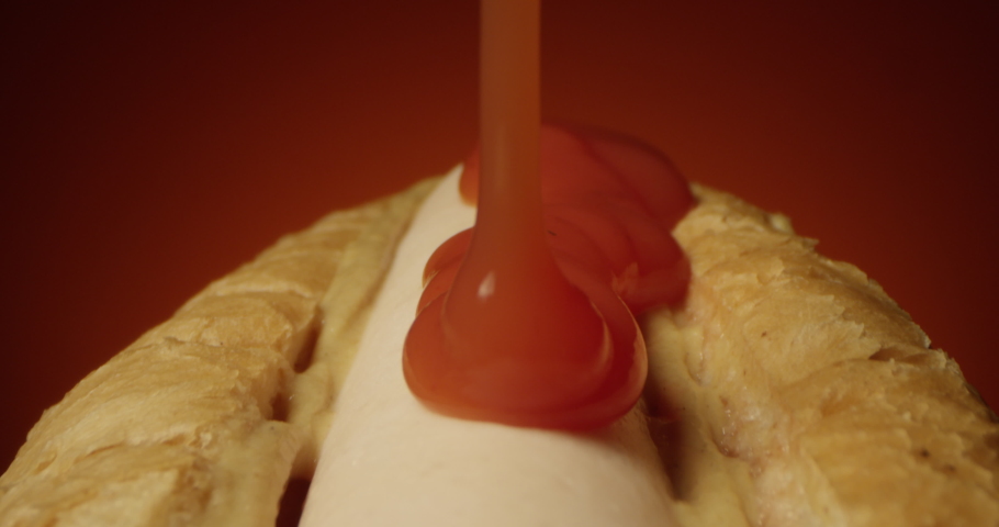 Ketchup Pouring on a Hot Dog with Sausage and Mustard on a Terra Cotta Background a Tracking Macro Shot of Hotdog with Laowa Lens Royalty-Free Stock Footage #1043958214