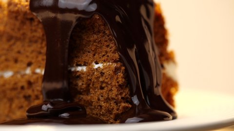 Chocolate icing on cake. Topping chocolate dessert. Chocolate glaze pouring on homemade dessert. Close up of biscuit cake decoration in 4K resolution
