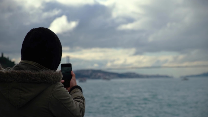 male photographing the Bosphorus view of Istanbul by mobile phone