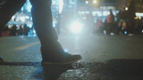 Casually dressed person walking on colorful busy city street at night.Low angle slow motion of a man crossing a vibrant backlit city intersection.Original 10 bit clip.