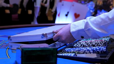 Dealer, croupier closes a suitcase with poker chips in a casino. Hands close up. Poker chips for gambling card games
