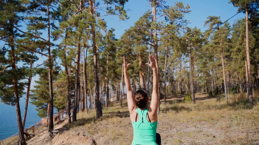 girl on a high riverbank does a workout. Charging before jogging.