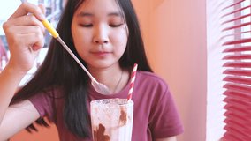 Young asian millennial woman drinking a milkshake in cute cafe, summer concept