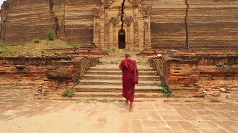 Asian Monk Walking In Front Of Burmese Ancient Buddhist Temple. 4K Slow Motion Footage. Mandalay, Myanmar.