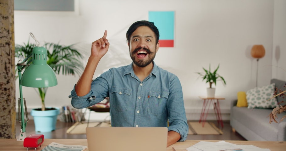 Moment of insight genial idea coming to mind of cute young man sitting with computer, enlightenment of cheerful brunette guy working at home office using laptop for job project document typing