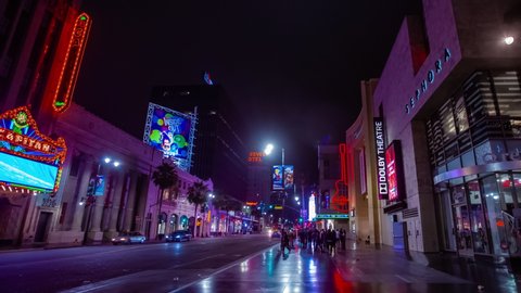 Hollywood, CA / USA - 12/1/2019: Time lapse in motion or hyper-lapse walking down Hollywood Boulevard in Los Angeles at night with signs, stars, lights and people passing by.