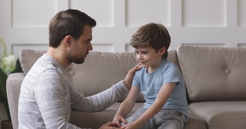Caring single young adult father comforting talk with preschool kid son at home, loving foster parent dad teach small child boy give advice psychological support express trust in relationship concept